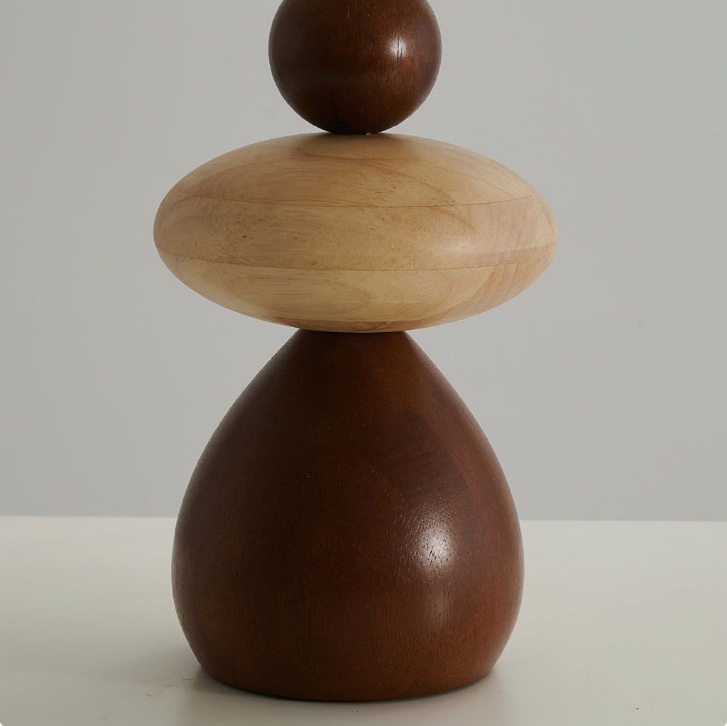 Close view of the stacked wood body of this Clérachic table lamp, a pale rounded disc between a walnut ball and a walnut base.