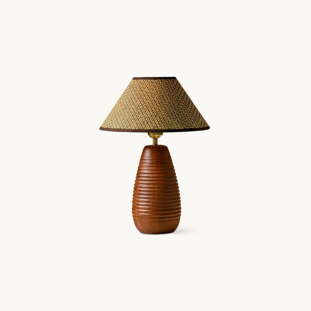 A Clérachic table lamp with a ribbed, walnut-colour wood base and a straw weave shade, on a plain off-white backdrop.