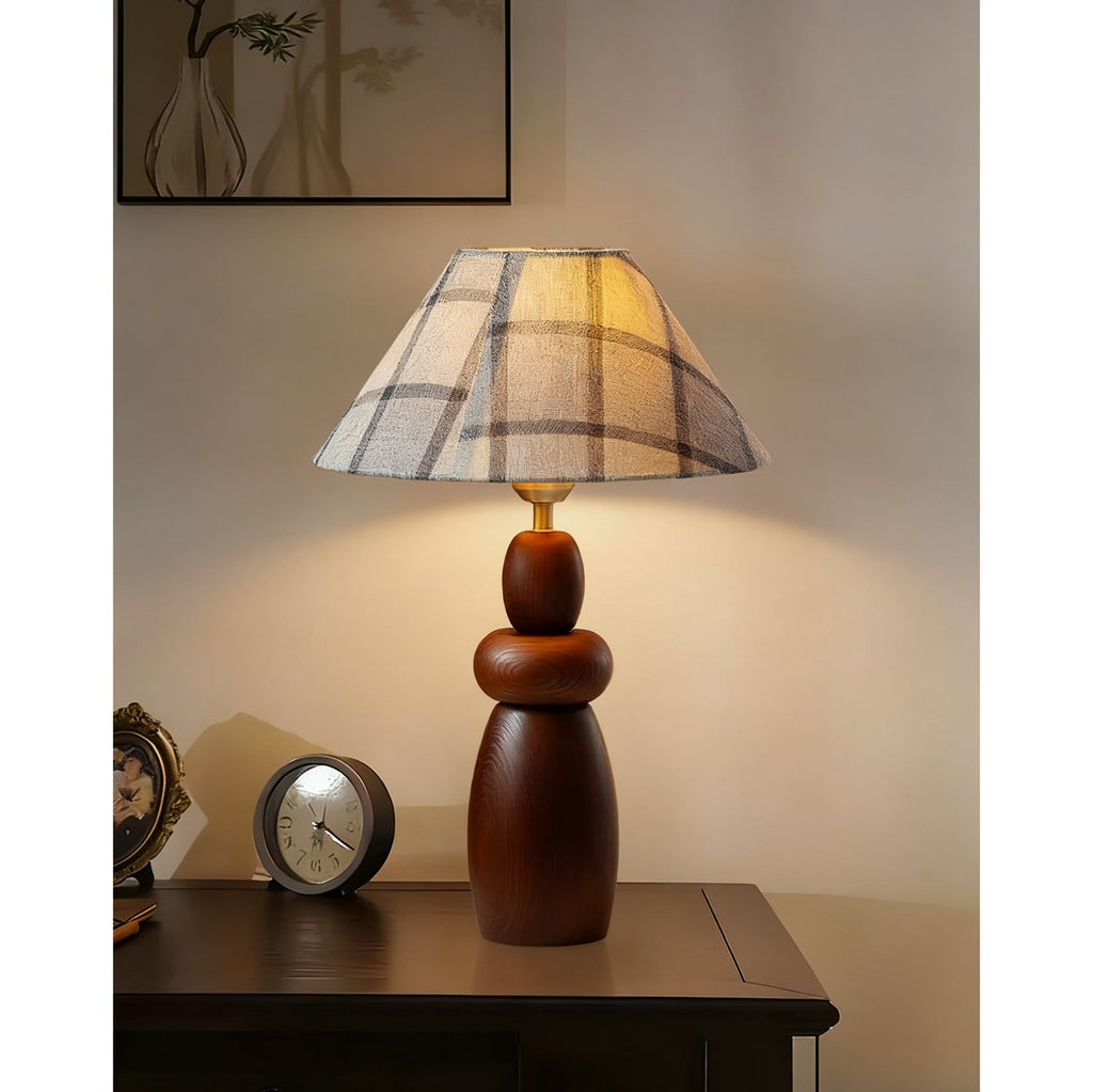 Lighting a dark console next to a small round clock, a Clérachic table lamp with a plaid shade and a stacked wood base.