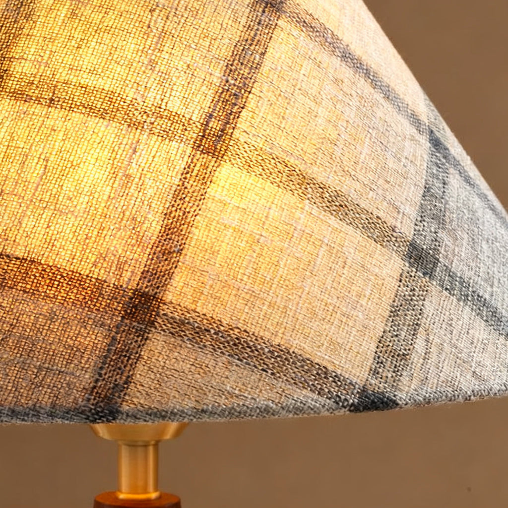 Close view of the plaid linen-look fabric on this Clérachic lamp shade, lit from within, above the brass neck.