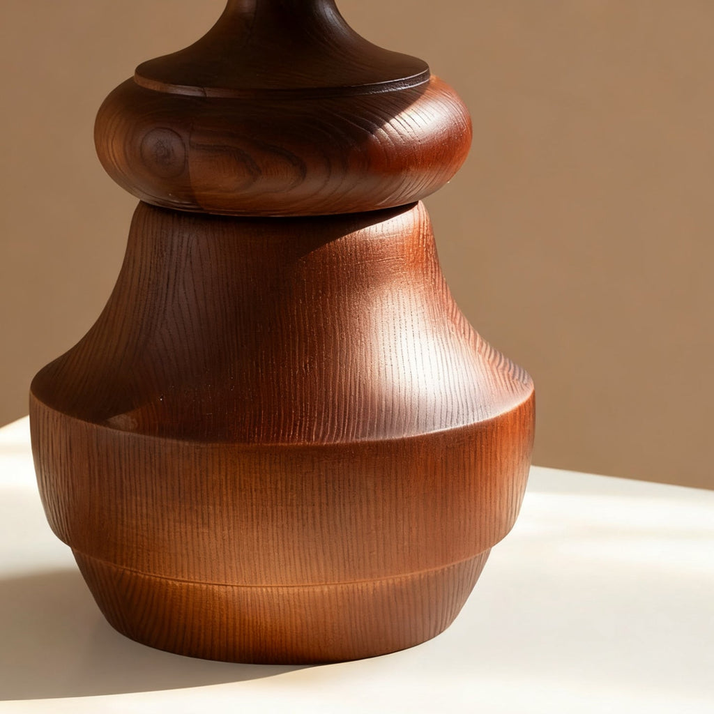Close view of the grain in the turned walnut-colour wood base of this Clérachic table lamp, on a white surface.