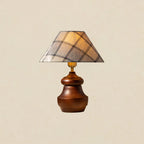A Clérachic plaid-shade table lamp with a wood base that curves out at the foot, on a soft beige backdrop.