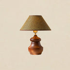 Wood base with a wide shoulder under a straw weave shade, this Clérachic table lamp on a soft beige backdrop.