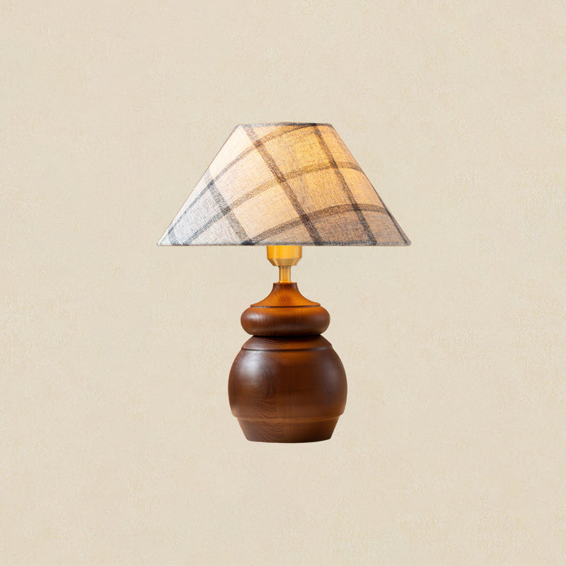 Plaid shade, brass neck and a smooth, rounded wood base on a Clérachic table lamp, shown on a plain beige backdrop.