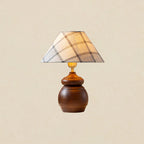 Plaid shade, brass neck and a smooth, rounded wood base on a Clérachic table lamp, shown on a plain beige backdrop.
