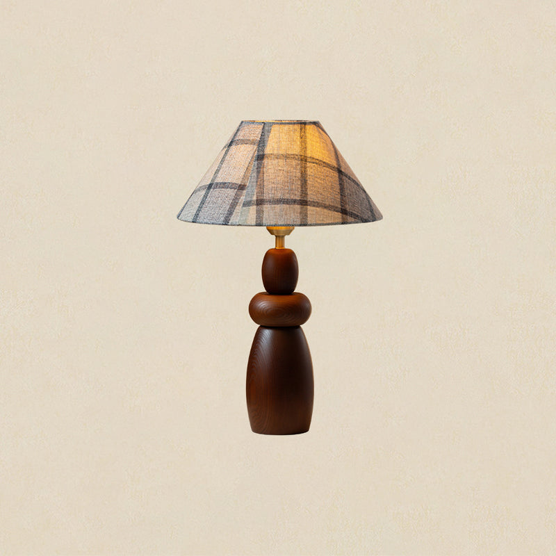 A tall Clérachic table lamp with a plaid shade and a stacked, tapering wood base, on a plain beige backdrop.