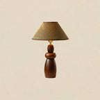 A tall Clérachic table lamp with a straw weave shade and a stacked, tapering wood base, on a plain beige backdrop.