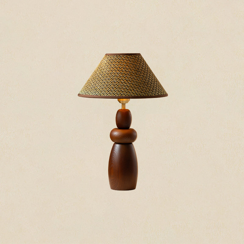 A tall Clérachic table lamp with a straw weave shade and a stacked, tapering wood base, on a plain beige backdrop.