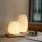 Two lit Clérachic lamps, round and tall, sit low on a tatami-style mat beside a small tea set and teal curtains.