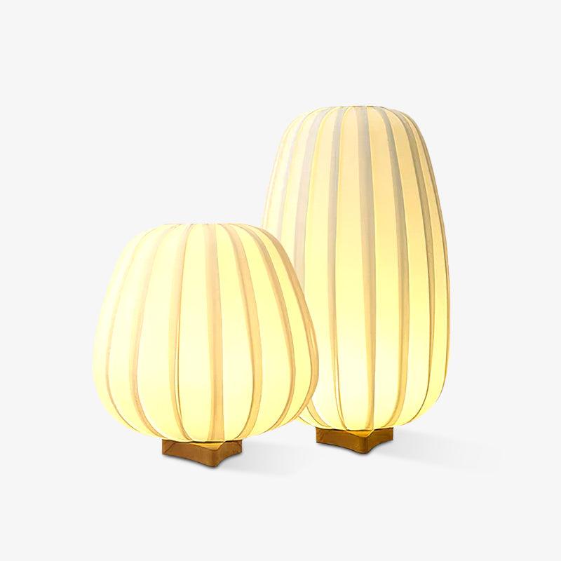 Two lit Clérachic table lamps on a white backdrop, their warm glow giving a soft shadow under each wooden base.