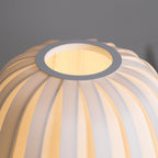 Close view of the round opening at the top of this lit Clérachic table lamp and the ribbed fabric around it.