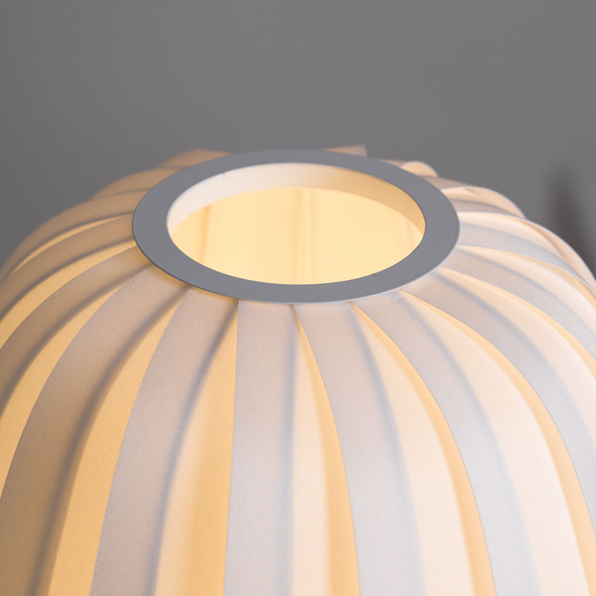 Close view of the round opening at the top of this lit Clérachic table lamp and the ribbed fabric around it.