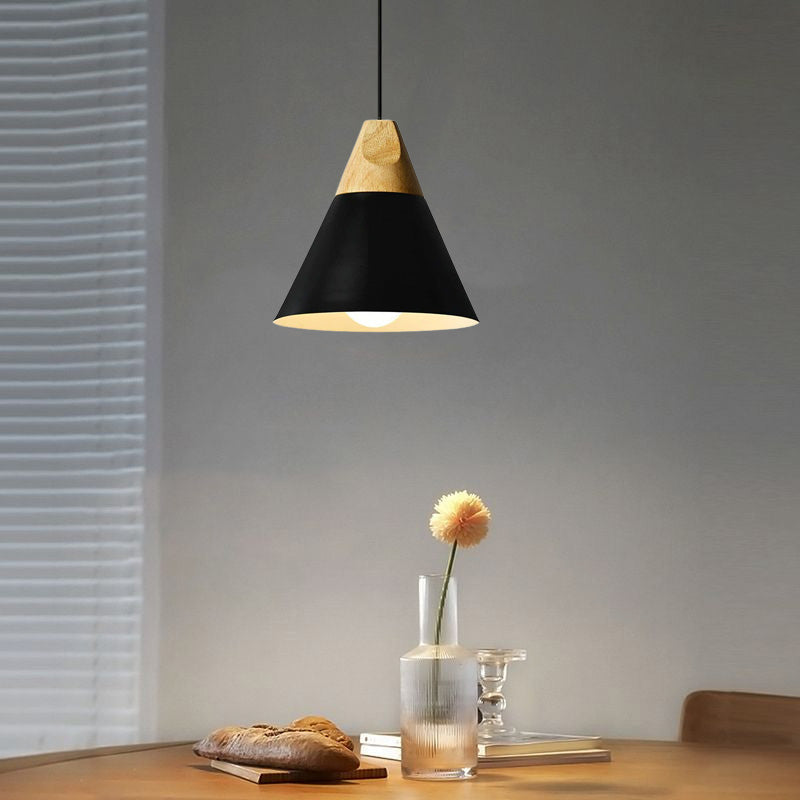 This black Clérachic cone pendant glows warmly above a rustic wood table set with bread and a bud vase.