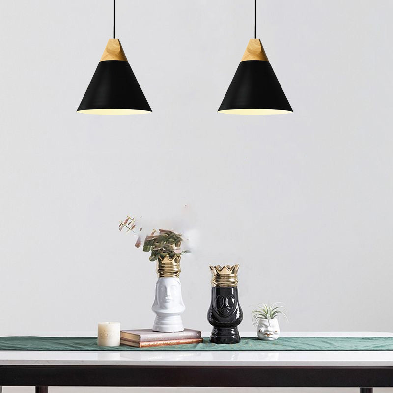 Two black Clérachic cone pendants, wood caps matched, are lit side by side above a console styled with crowned vases.