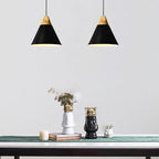Two black Clérachic cone pendants, wood caps matched, are lit side by side above a console styled with crowned vases.