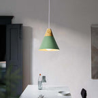 The green Clérachic cone pendant glows above a white dining table, its wood cap and cord clearly visible.
