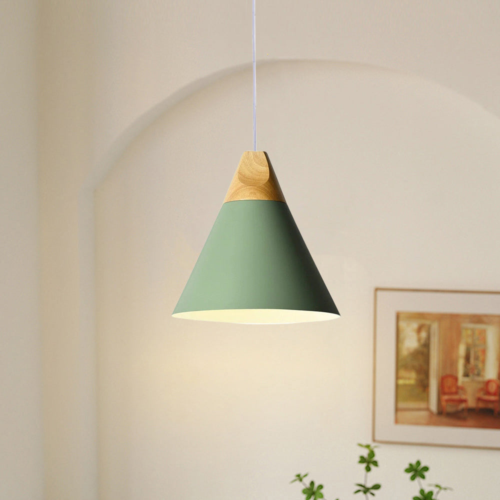 Close-up of the wide green Clérachic cone pendant lit in an arched alcove, its bulb glow spilling onto the wall.