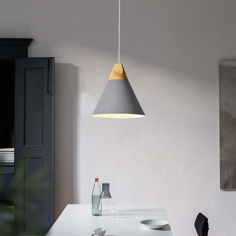 The grey Clérachic cone pendant glows above a white dining table, its matte finish and wood cap on display.