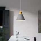 The grey Clérachic cone pendant glows above a white dining table, its matte finish and wood cap on display.