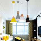 Four Clérachic cone pendants in yellow, grey, white, and black hang at staggered heights above a living-room sofa.