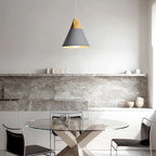 A grey wide Clérachic cone pendant hangs above a round glass dining table in a marble-backsplash kitchen.