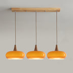 Clérachic Wood-Top Glass Pendant Light in the three-head amber version, lit shades spaced evenly along the wood ceiling bar.