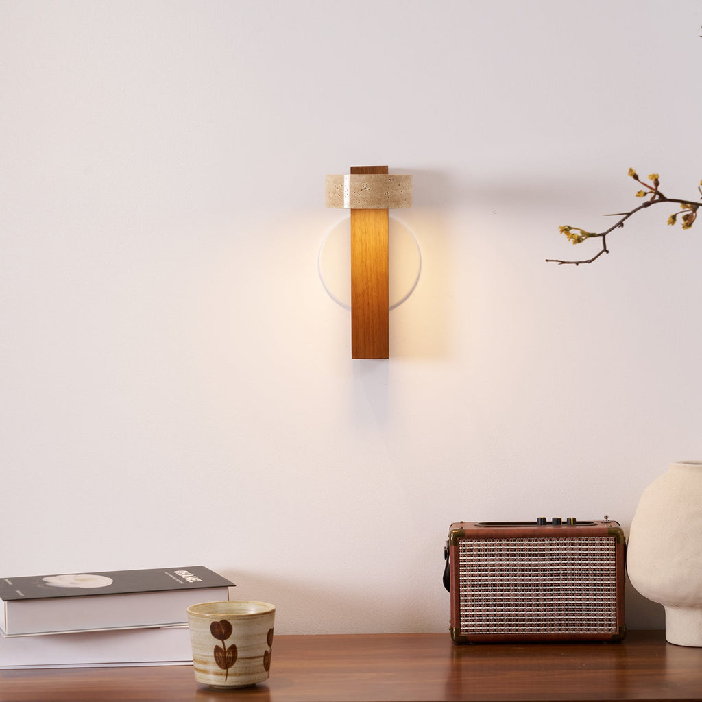 A small Clérachic wall light glows above a wooden console holding a retro radio, a cup, books and a cream vase.
