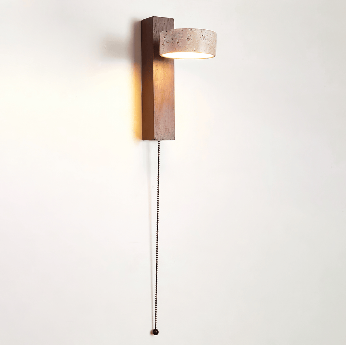 This Clérachic wall light with a walnut-coloured bar and a travertine head has a beaded pull cord hanging down a white wall.