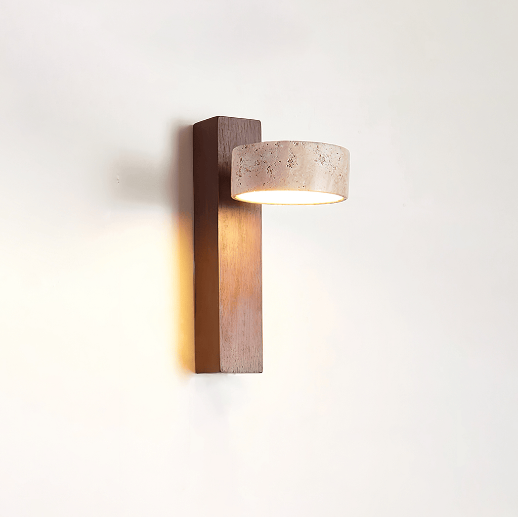 Side view of this Clérachic wall light, with a dark walnut-coloured bar and a travertine head facing out, glowing warm on a white wall.