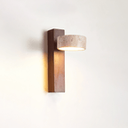 Side view of this Clérachic wall light, with a dark walnut-coloured bar and a travertine head facing out, glowing warm on a white wall.