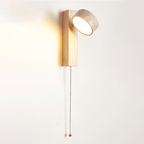 The pale wood version of this Clérachic wall light has its travertine head tilted up, with a beaded pull cord hanging below.