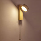 Glowing against a warm taupe wall, this Clérachic wall light in pale wood has its travertine head tilted upwards and a pull cord below.