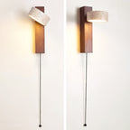 Two views of a Clérachic wall light in walnut-coloured wood with a pull cord, one with its head tilted up and lit, one with it turned out.