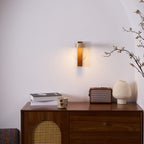 A Clérachic wall light glows in an arched alcove above a walnut sideboard with a cane front, a retro radio and a cream vase.