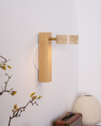 A Clérachic wall light in pale wood with its travertine head swung out sideways, above a retro radio and a cream vase.
