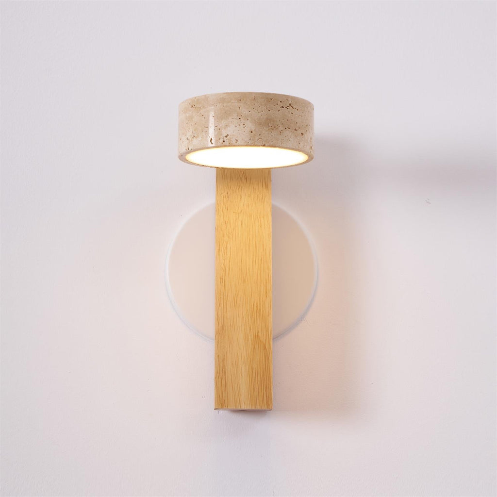 Front view of this Clérachic wall light in pale wood, with a travertine head lit underneath and a round white wall plate behind.