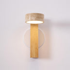 Front view of this Clérachic wall light in pale wood, with a travertine head lit underneath and a round white wall plate behind.