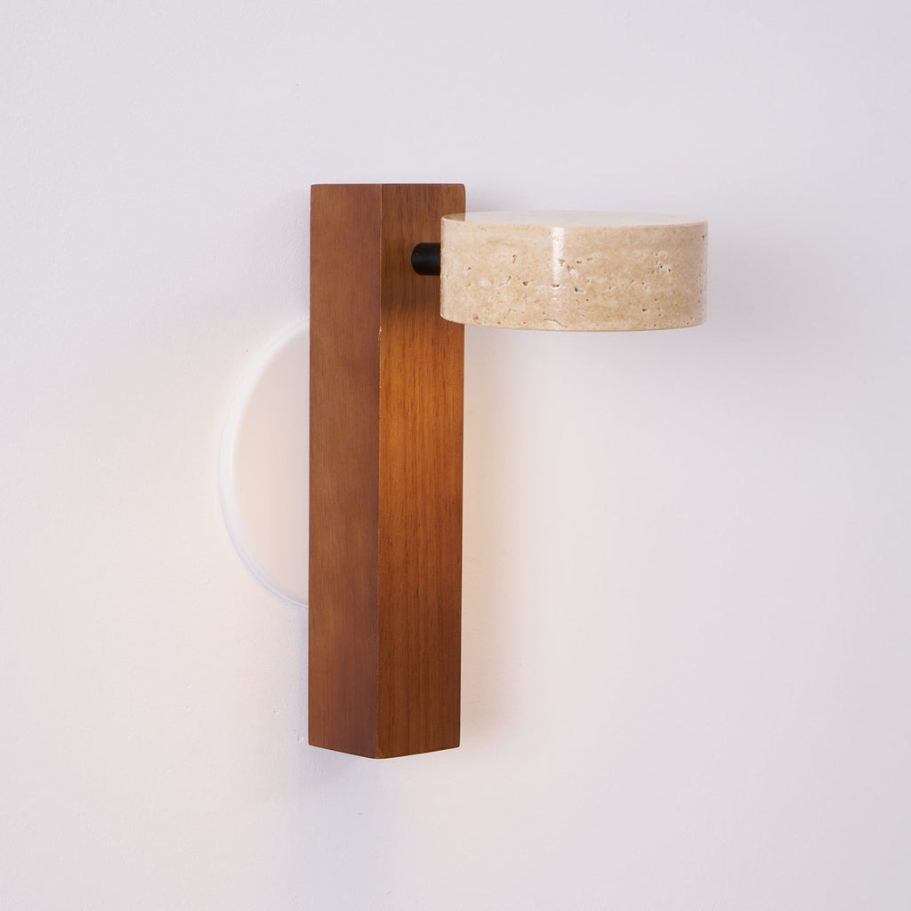 Side view of this Clérachic wall light with a walnut-coloured bar, its travertine head turned out from a black pivot.