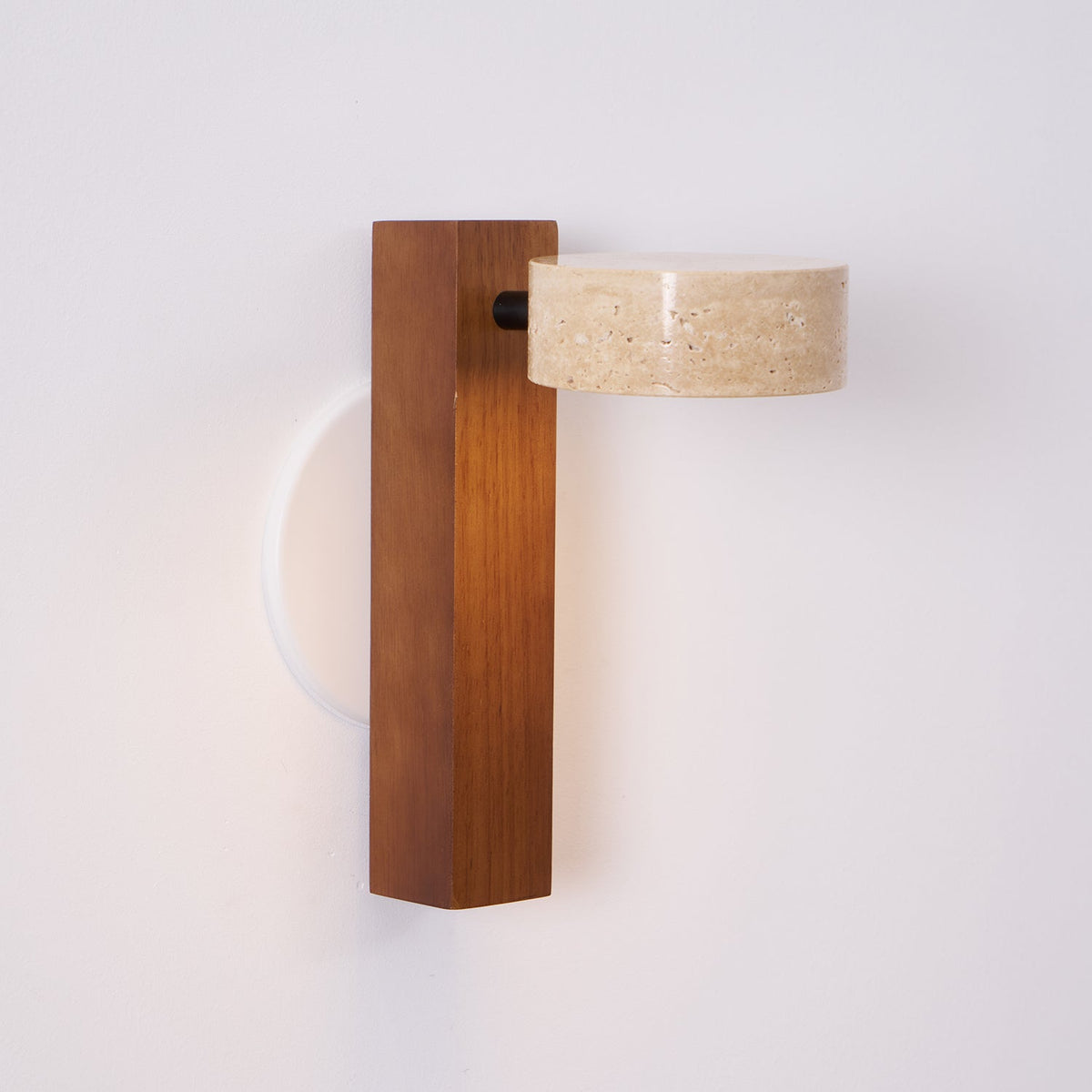 Side view of this Clérachic wall light with a walnut-coloured bar, its travertine head turned out from a black pivot.