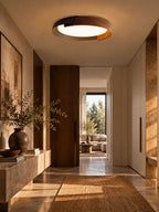 A black and dark wood Clérachic ceiling light lit above a hallway with a stone console, a sisal runner and a dark vase.