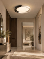 A black and white Clérachic ceiling light lit above a hallway, with a mirror, a stone console and a view to a sunny room.