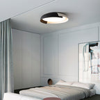A black and dark wood Clérachic ceiling light lit above a grey bedroom, with a green curtain and a low white bed.