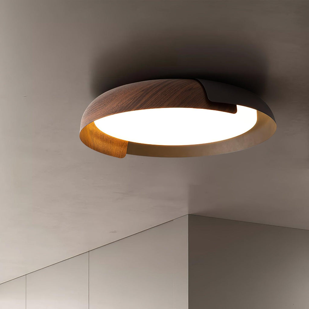 Close view of a dark wood and black Clérachic ceiling light with a frosted lit centre, against a grey ceiling.
