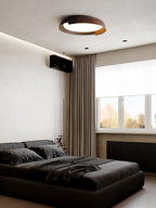 A black and dark wood Clérachic ceiling light lit in a grey bedroom with dark bedding, brown curtains and a window.