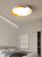 A light wood and white Clérachic ceiling light lit in a bedroom with a pale wall strip light and a line-art print.