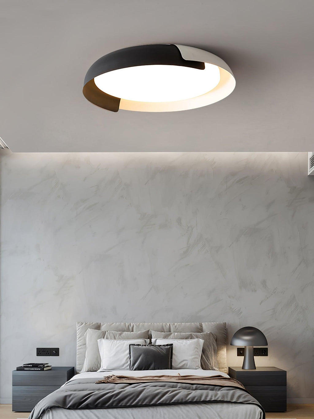 A grey and wood Clérachic ceiling light lit above a bed with dark bedding, a mushroom table lamp and a plaster-effect wall.