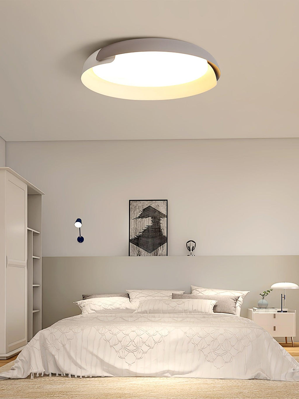 A white and light grey Clérachic ceiling light glows above a bed with white linen and a framed print, in a calm bedroom.