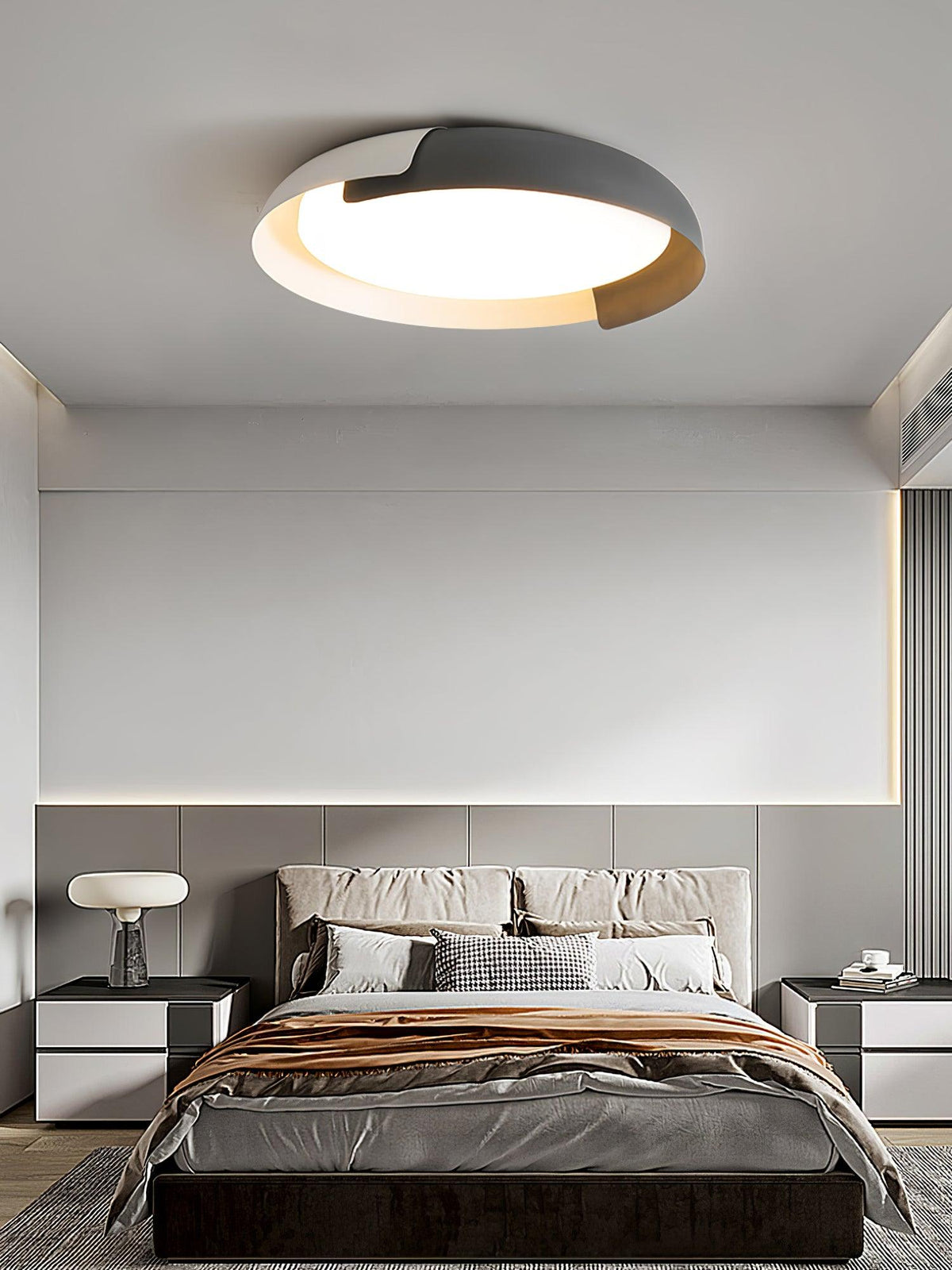 A grey and wood Clérachic ceiling light glows above a bed with a copper-toned throw, in a grey bedroom with a table lamp.