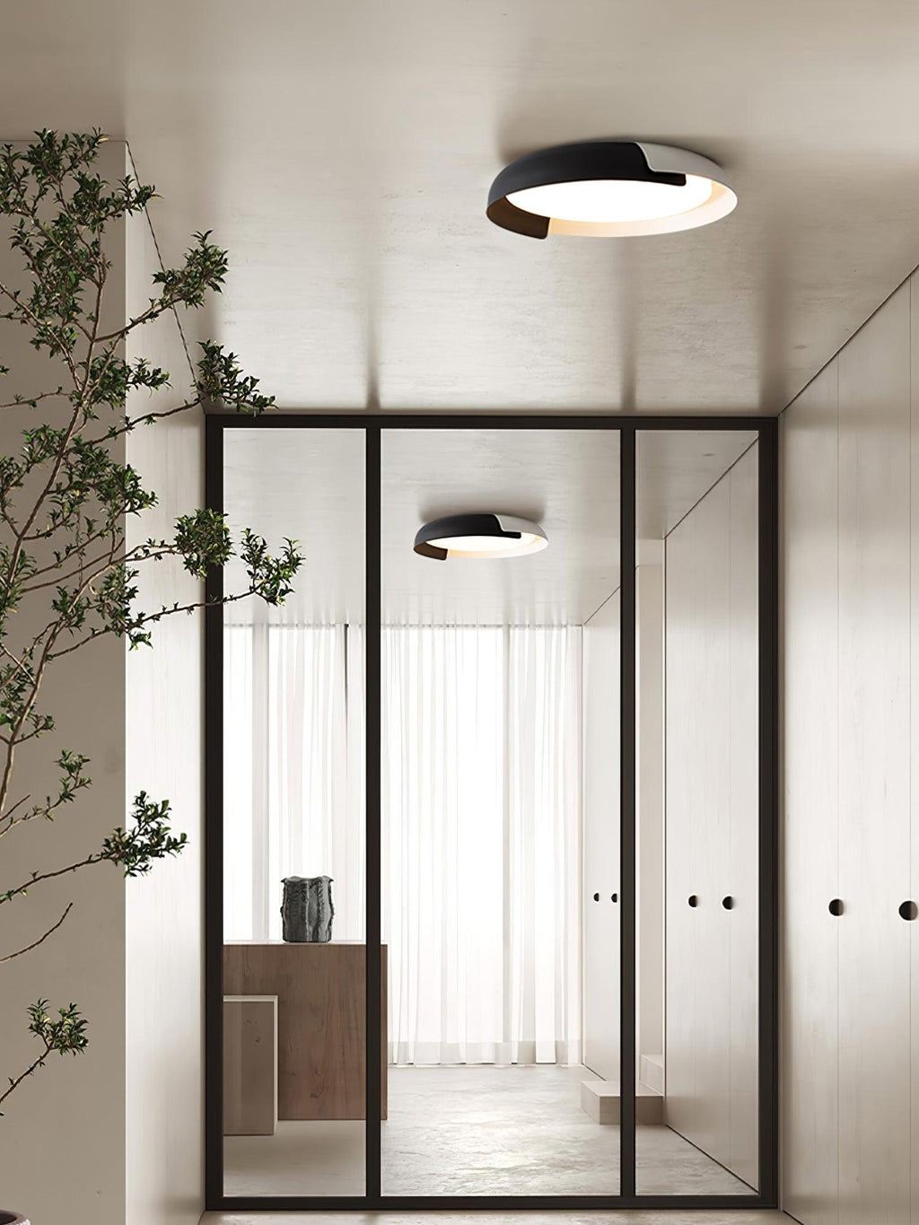 A black and white Clérachic ceiling light lit in a hallway with a glass door, with a second light visible beyond the glass.