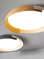 Close view of a light wood and white Clérachic ceiling light with a second grey and wood one below, on a grey backdrop.